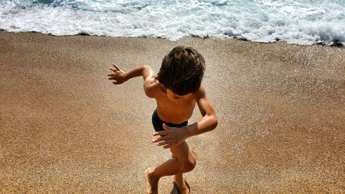 Shirtless boy running at sea shore