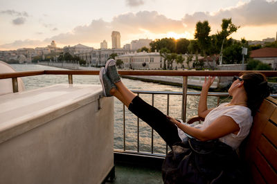 Woman sitting in ferry boat during sunset