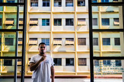 Portrait of young man standing against building