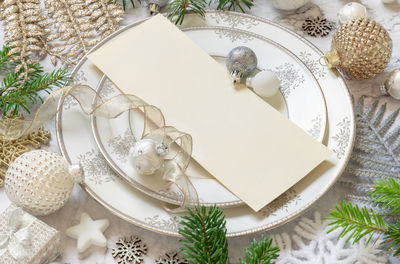 Festive table setting with a card, ornaments and fir tree branches top view