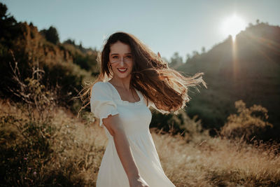 Portrait of smiling young woman standing on field