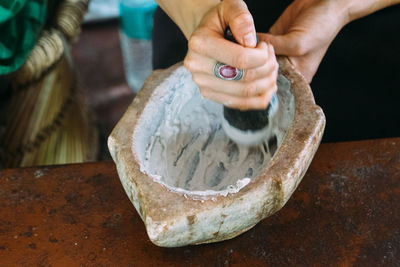 Close-up of woman mortar and pestle while preparing food at table