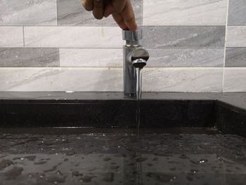 Cropped hand touching faucet