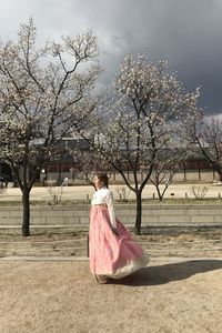 Rear view of woman with trees against sky