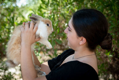 Side view of woman holding bird against blurred background