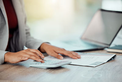 Midsection of woman using laptop on table