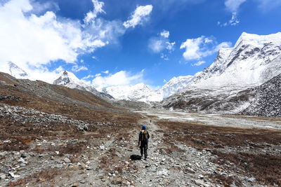 Rear view of hiker carrying backpack while standing on snow covered mountain