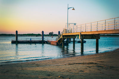 Pier over sea against clear sky during sunset