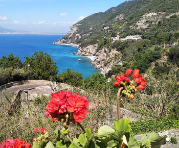 Scenic view of sea by mountain against sky