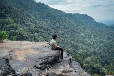 Man sitting on rock looking at mountains