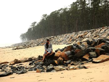 Smiling woman sitting on rocks at beach