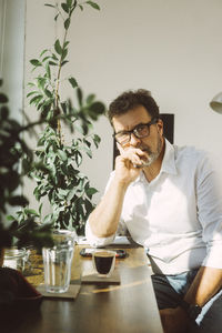 Serious businessman leaning on elbow at office coffee corner