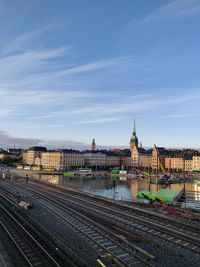 Railroad tracks by buildings in city against sky