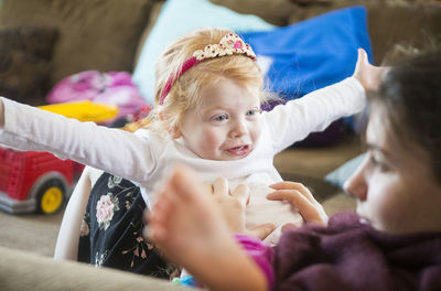 Young girl playing with woman on sofa