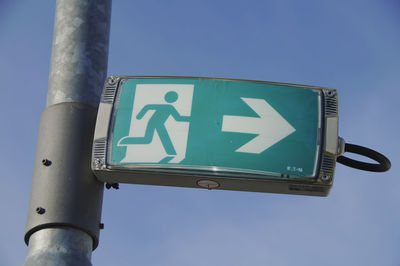 Low angle view of road sign against clear blue sky