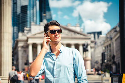 Young man using mobile phone in city