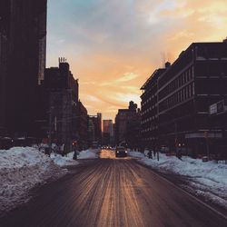 Empty road along built structures in winter