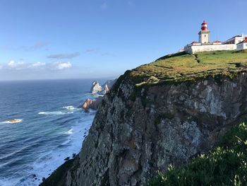 Lighthouse by sea against sky