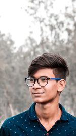 Smiling young man in eyeglasses looking away while standing outdoors