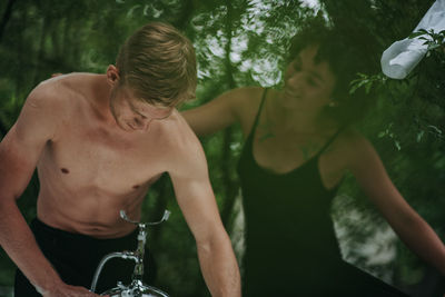 Midsection of shirtless man and woman in water