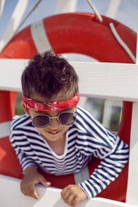 Child boy in striped clothes and red pants  standing on beach. white lifeguard tower, with a circle