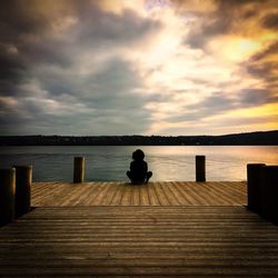 Silhouette bench on sea shore against sky