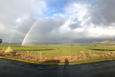 Scenic view of rainbow over land against sky