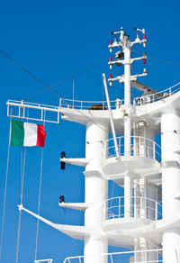 Low angle view of flags against clear blue sky