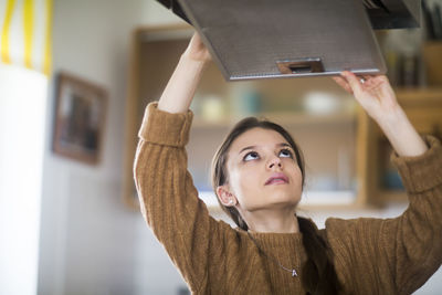 Young woman cleaning fan in the kitchen