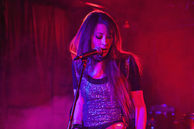 Beautiful young woman wearing red mask at night