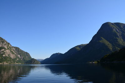Scenic view of lake and mountains against clear blue sky
