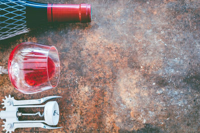 High angle view of wine bottle by wineglass on weathered table