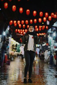 Full length portrait of young woman standing at night