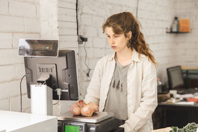 Grocer weighing onions on weight scale in shop