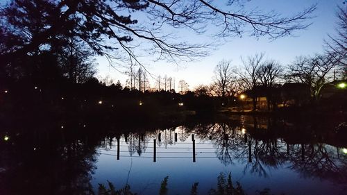 Reflection of silhouette trees in lake against sky