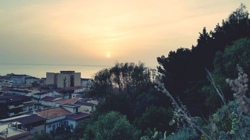 High angle view of townscape by sea against sky at sunset