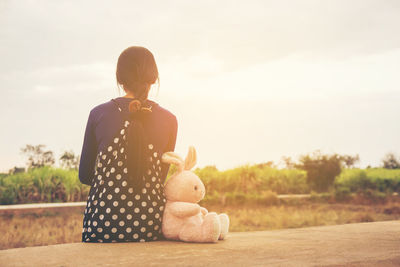 Rear view of girl sitting at toy against sky