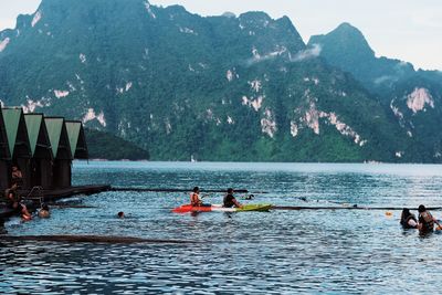 People on boat against mountain range