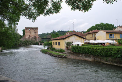 Houses by river against sky