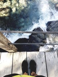 Low section of woman standing by water