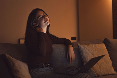 Young woman sitting on sofa at home