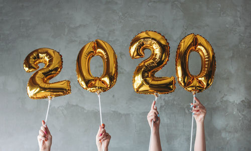 Cropped hands holding balloons against wall