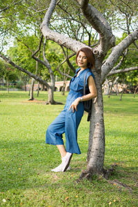 Portrait of smiling woman standing by tree