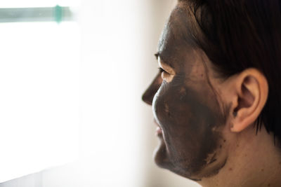 Close-up of woman wearing facial mask against wall