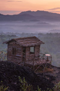 Abandoned building by mountain against sky during sunset