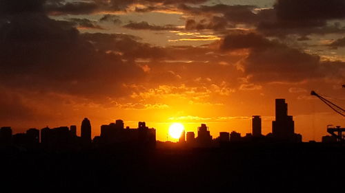 Silhouette of city against sky during sunset