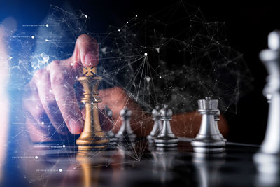 Digital composite image of person touching chess piece on table