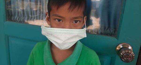 Close-up portrait of boy wearing mask against door