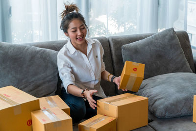 Smiling young woman sitting on sofa in box