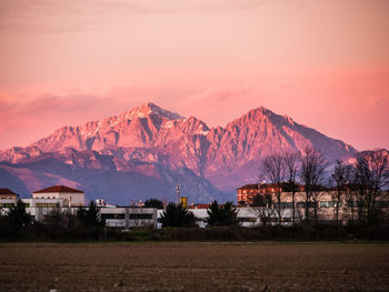 Scenic view of houses and mountains against sky during sunset